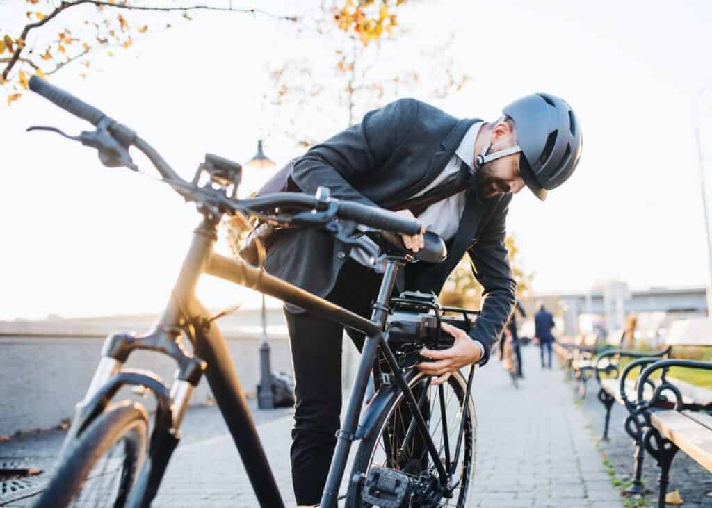 A helmeted rider checking an electric bike beside a city path